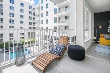 A balcony with two chairs and a bench and a pool